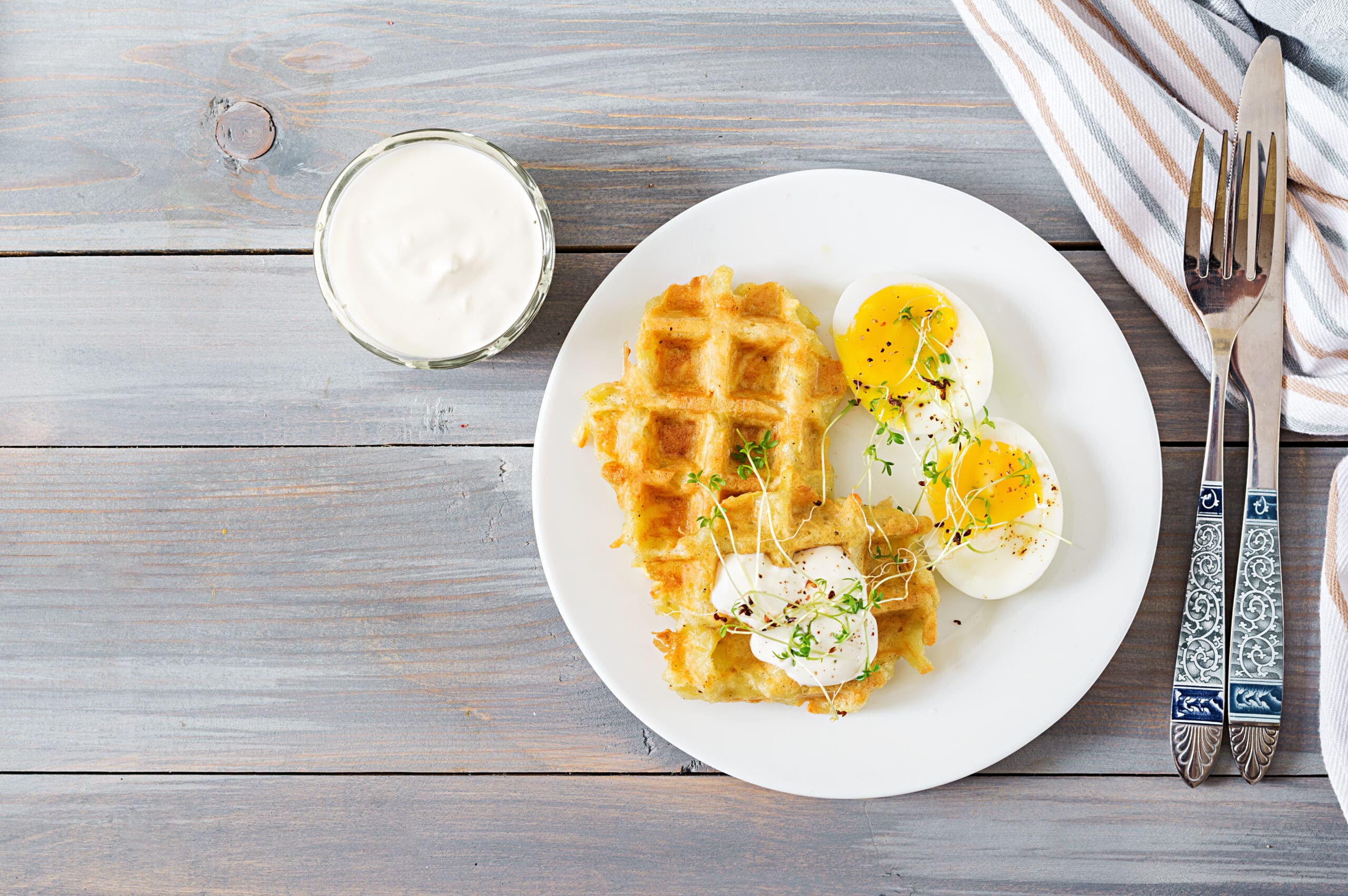 Healthy breakfast or snack. Potato waffles and boiled egg on grey wooden table. Top view. Flat lay